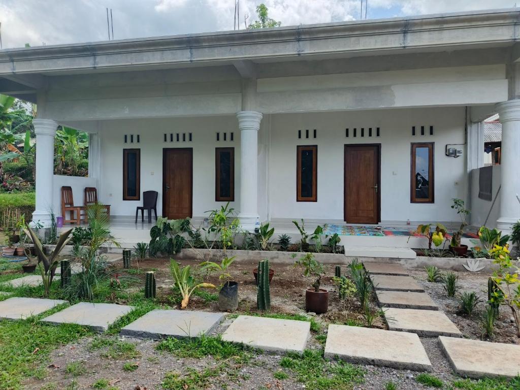a white house with a garden in front of it at Tetebatu Backpackers Base in Selong