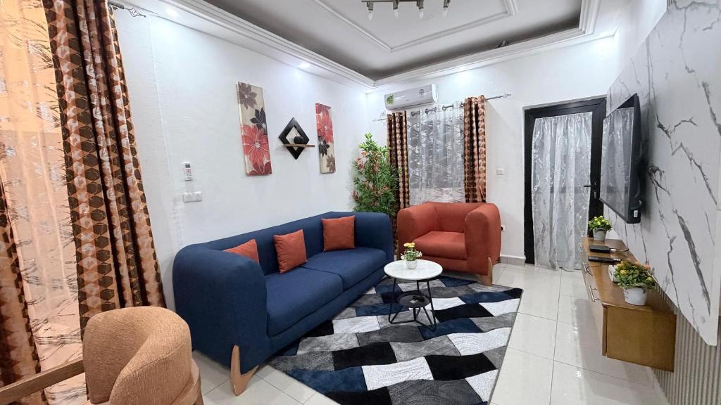 a living room with a blue couch and two chairs at Eva Apparts "situé à Kotto Baden Baden" - PARKING CAMERA BALCON WIFI CLIM CONFORT in Douala
