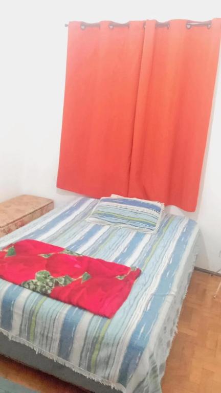 a bed in a room with a red curtain at Pousada May in Ribeirão Preto