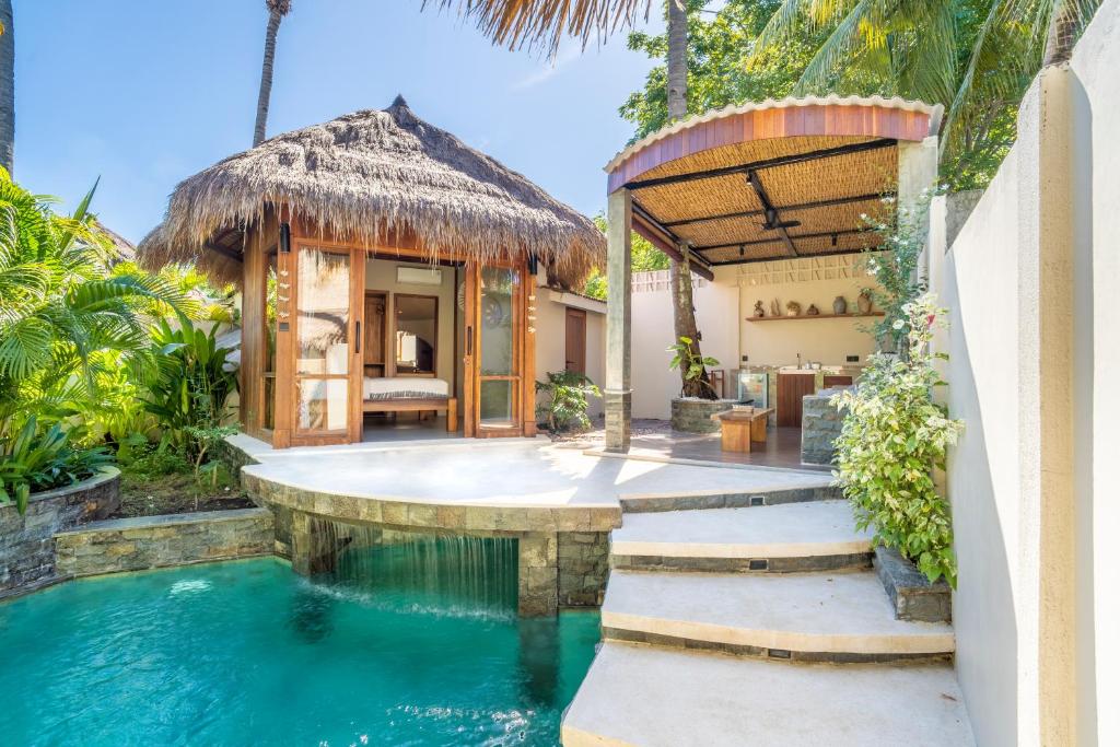 an infinity pool in a villa with a thatch roof at MELO Gili Air in Gili Islands