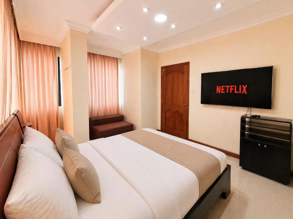 Exclusive Executive & Couple Suite con Piscina في ماتشالا: غرفة فندق بها سرير وتلفزيون