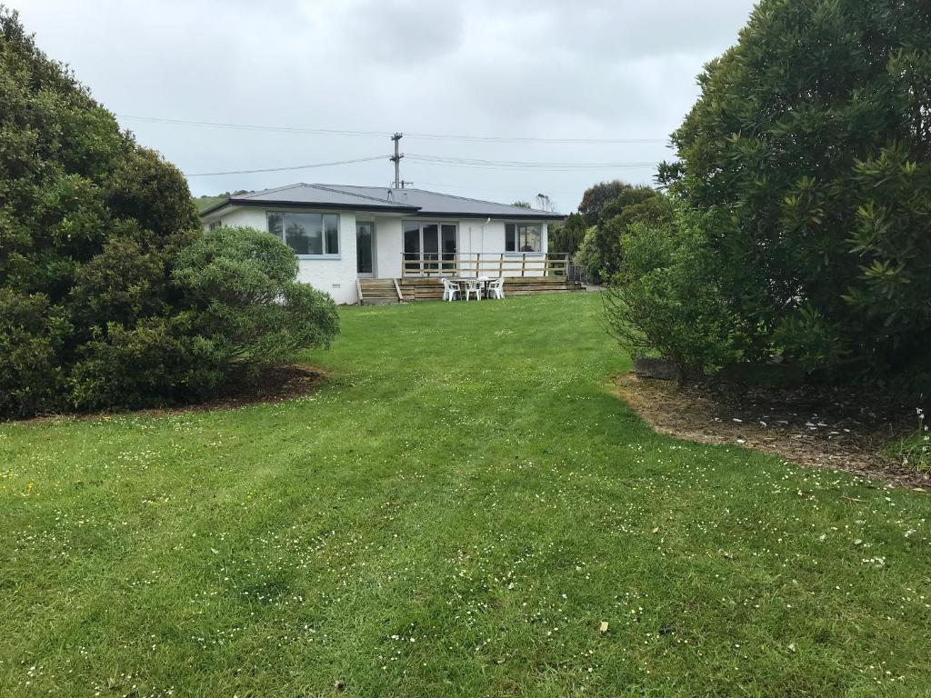 a house with a large yard in front of it at Cosy Beach House in Riverton