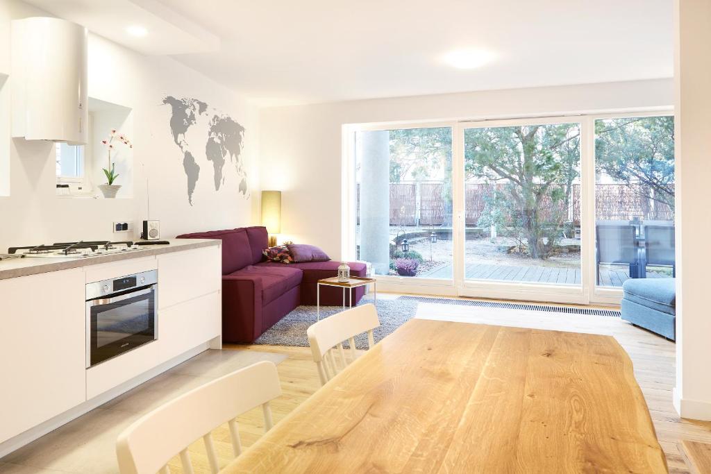 a kitchen and a living room with a wooden table at Lovely LUX Garden Flat near Royal Park in Warsaw