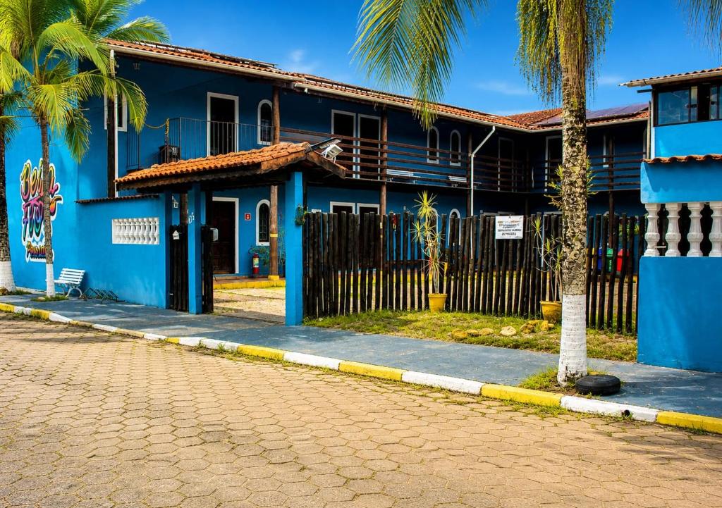 a blue building with palm trees in front of a street at Beija Flor Pousada in Ubatuba