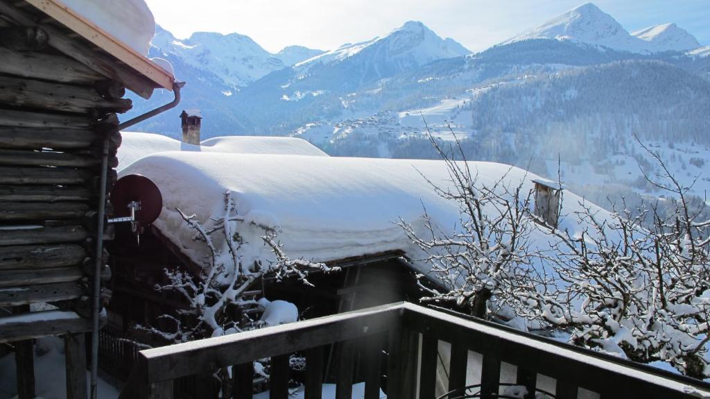 a snow covered roof of a cabin with mountains in the background at Ferienwohnung Graubünden/ Castiel in Castiel