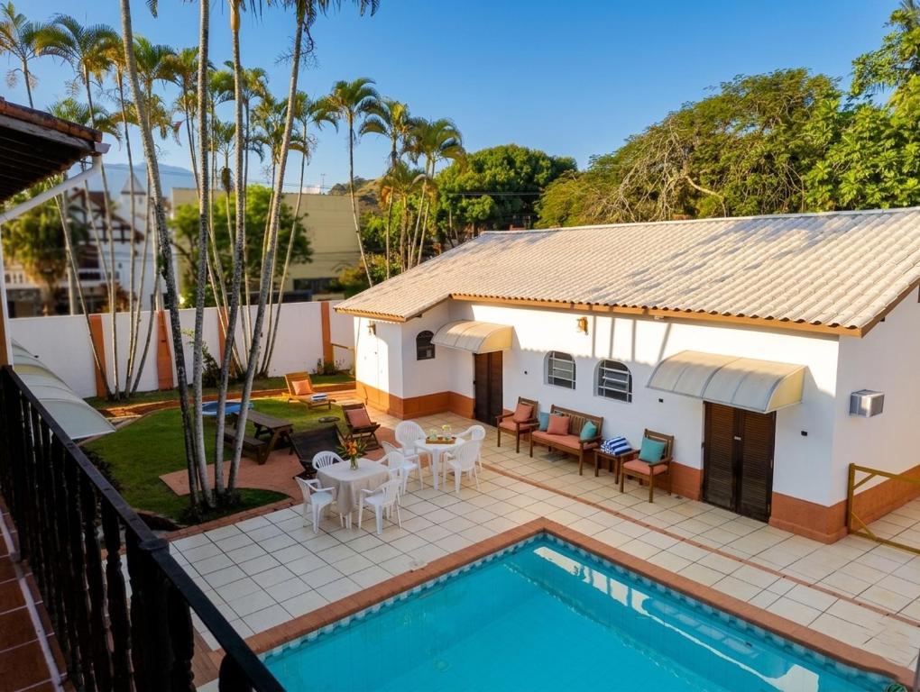 a house with a swimming pool and a patio with tables and chairs at Cantinho no litoral a 100mts da praia in São Sebastião