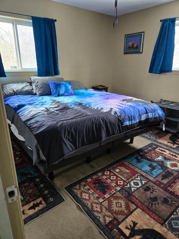 a bedroom with a bed with blue sheets and blue curtains at Lillian's Cozy Corner in Palmer
