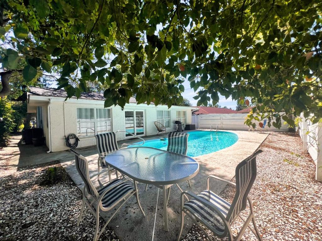 a patio with a table and chairs next to a pool at The Oasis - 2 Private Homes, Pool, and BBQ in New Port Richey