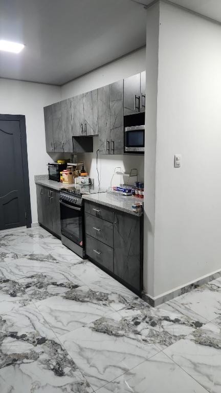 a kitchen with gray cabinets and a marble floor at Casa Lujosa in Choluteca