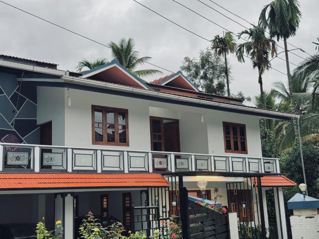 a white house with palm trees in the background at Chills homestay in Kalpetta