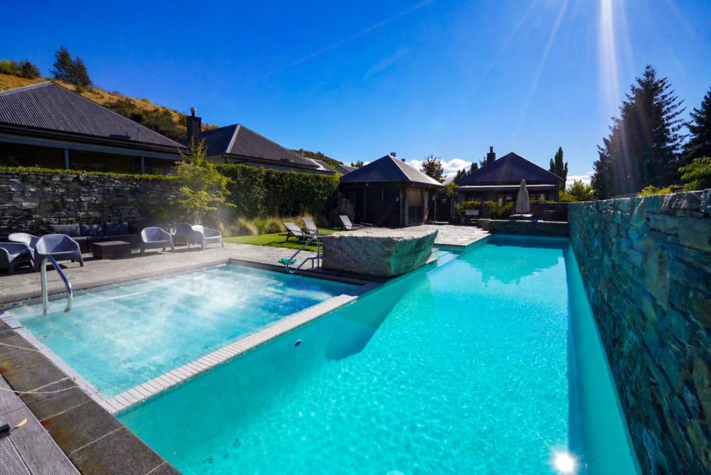 a swimming pool with blue water in a backyard at Cardrona Ridge by Aotearoa Escapees in Cardrona