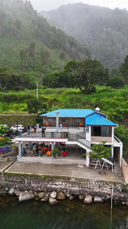 a building with a blue roof next to a body of water at Casmel Escape Hostel in Silalahi