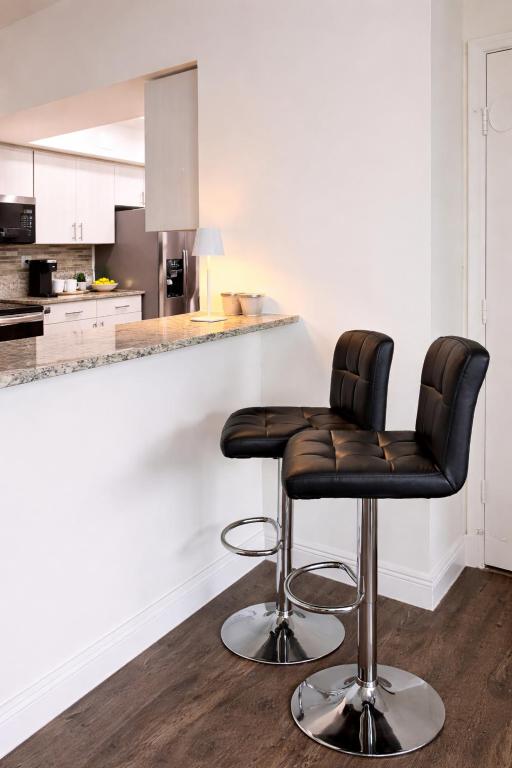 a kitchen with two bar stools in front of a counter at 2b apartment by the Ocean in Sunny Isles Beach