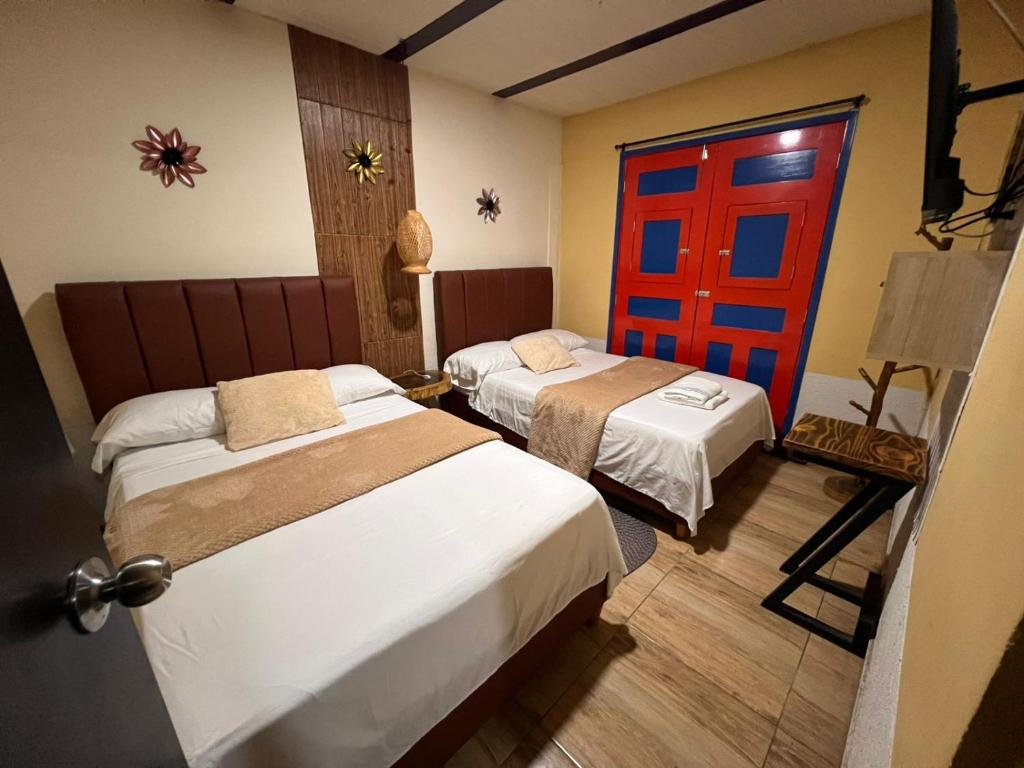 a hotel room with two beds and a red door at Hospedaje Salento in Salento