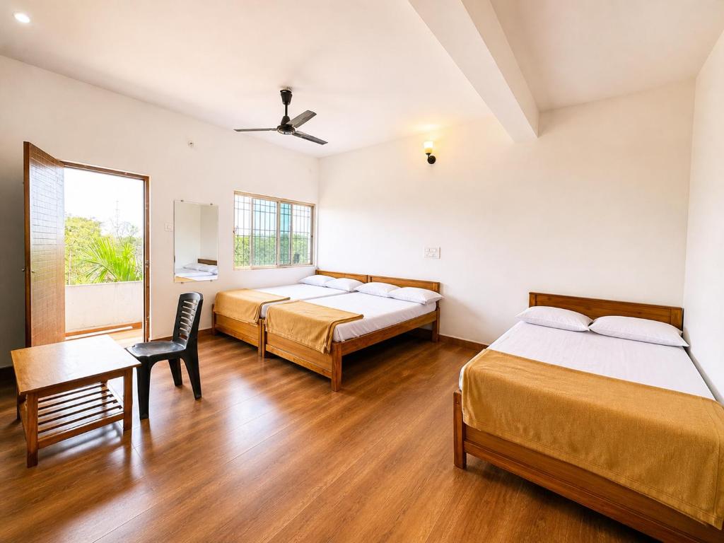 a room with three beds and a table and a window at hotel raj palace in Londa