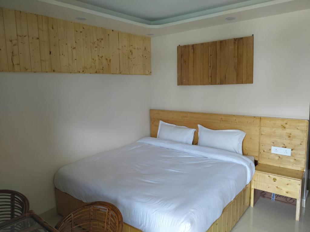a bedroom with a bed with white sheets and wooden cabinets at Bhagirathi Homestay in Joshīmath