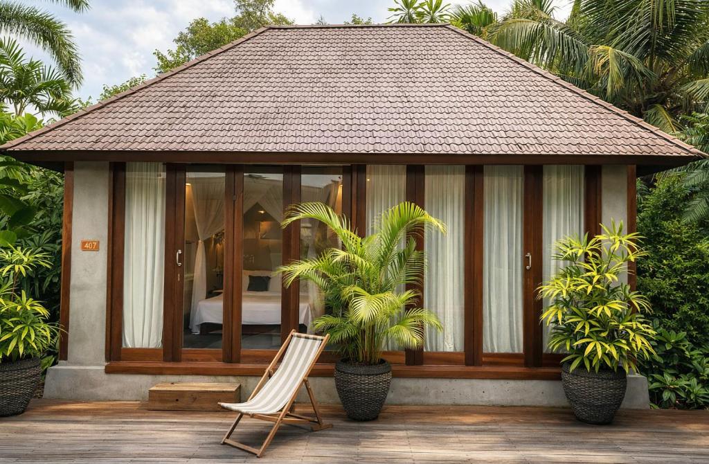 a gazebo with a chair and a bed at ZIN Berawa Villas & Bungalows in Canggu