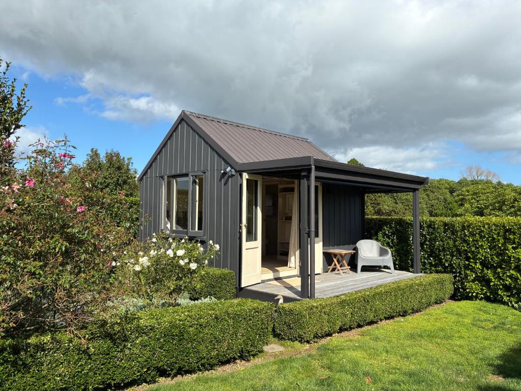 a small black shed with a deck in a garden at Tswalu in Raglan