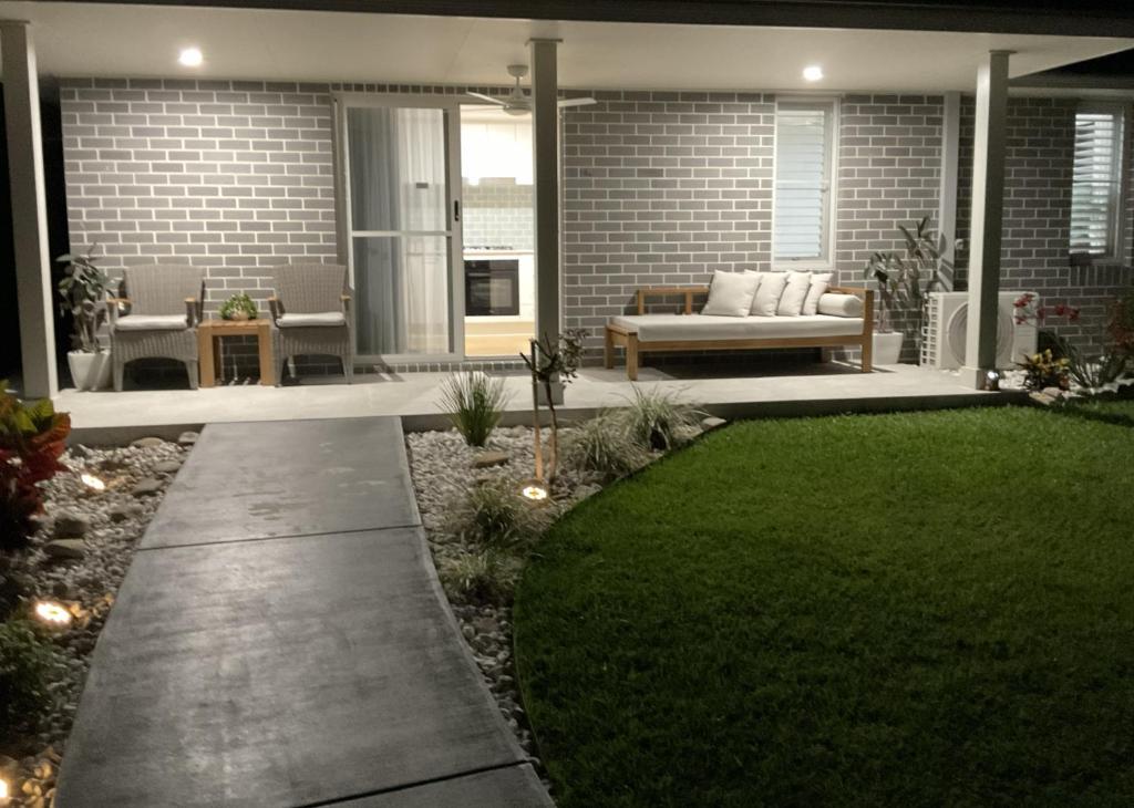 a backyard with a patio with a grass yard at Chay's Guest House in Coffs Harbour