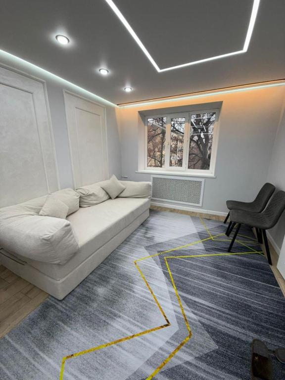 a living room with a white couch and a chair at Квартира на Толе би in Taraz