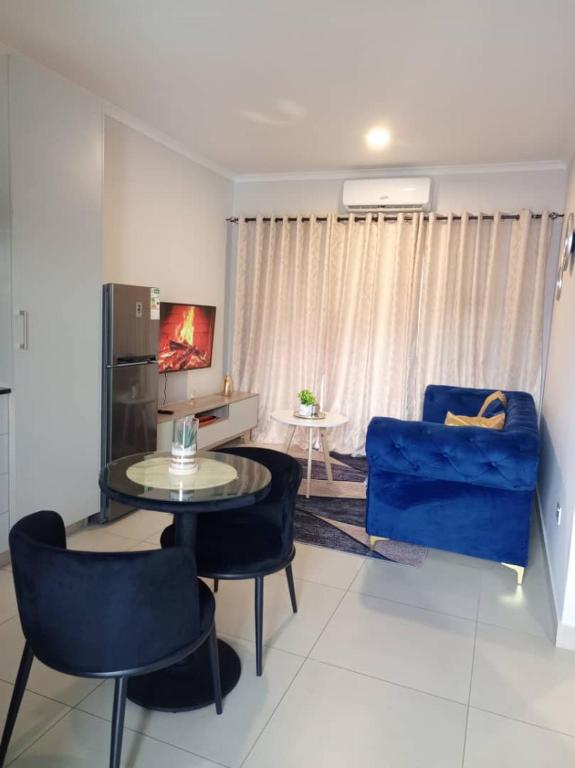 a living room with a blue couch and a table and chairs at Amos in Gaborone
