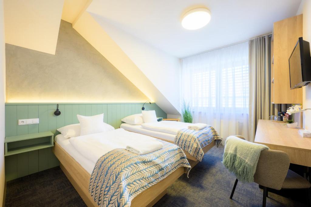 a hotel room with two beds and a desk at Hotel Roudna in Pilsen
