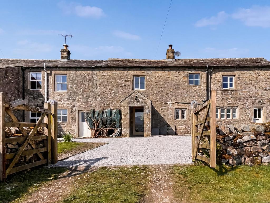 an old stone house with a gate and a barn at Holme House in Halton Gill
