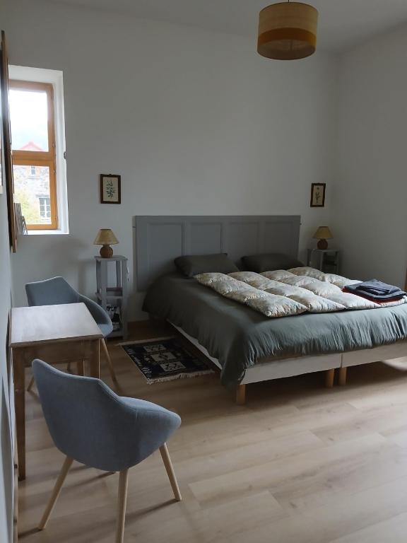 a bedroom with a bed and a chair and a table at Gradine et Boucharde in Le Monastier sur Gazeille
