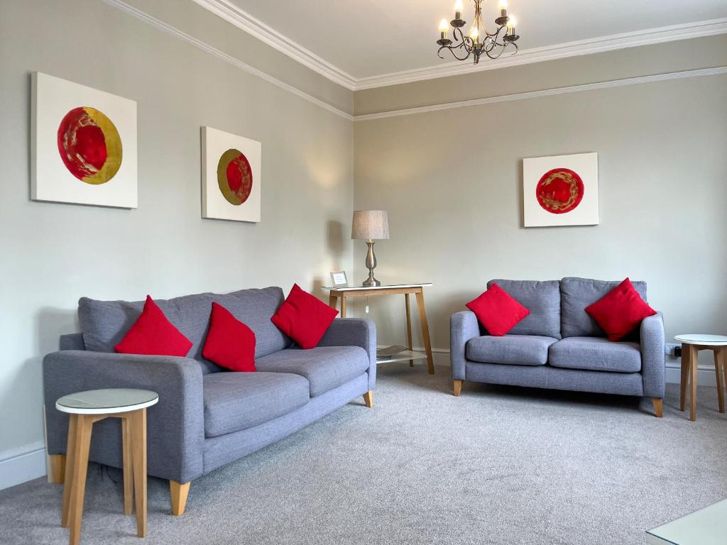 a living room with two couches and red pillows at Victoria Apartment 1 in Tarporley