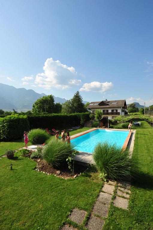 a group of people standing around a swimming pool at Hotel Villnerhof in Egna