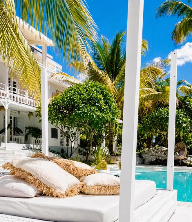 a bed in front of a villa with a swimming pool at Cocoon Signature in Flic-en-Flac