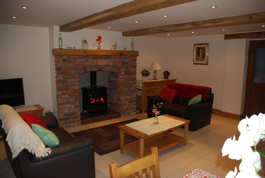 a living room with a fireplace and a couch at Swallows Barn Cottage in North Rode