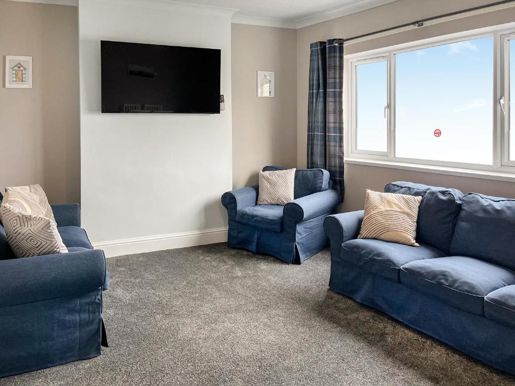 a living room with two blue couches and a flat screen tv at Primrose - Uk49360 in Bridlington