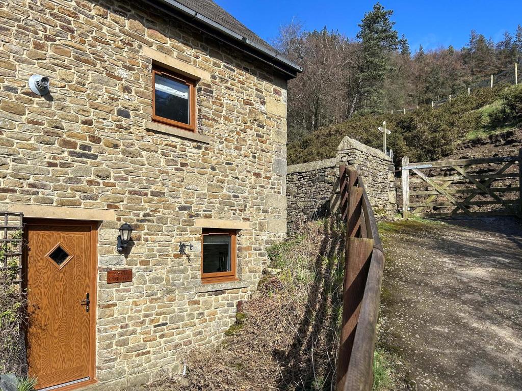 a stone building with a wooden door next to a fence at Birch Cottage - Ukc9267 in Hope