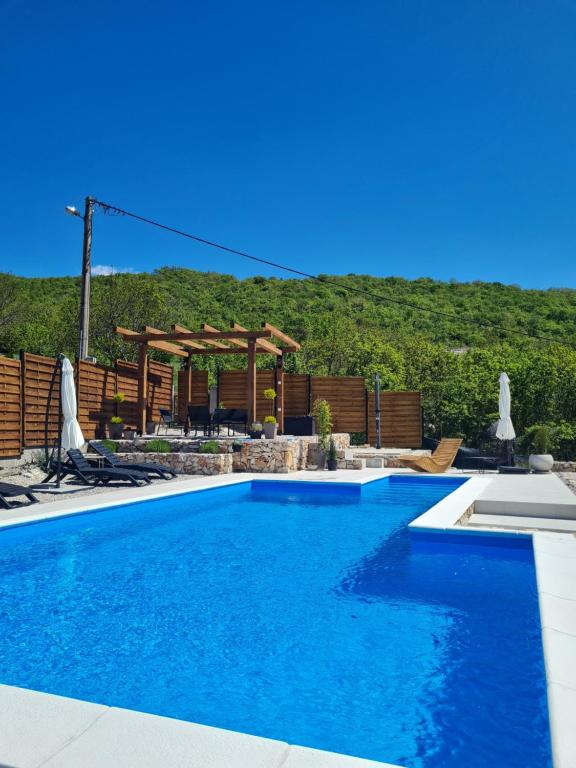 a swimming pool in front of a fence with a mountain at Kamena kuća Goranci in Mostar