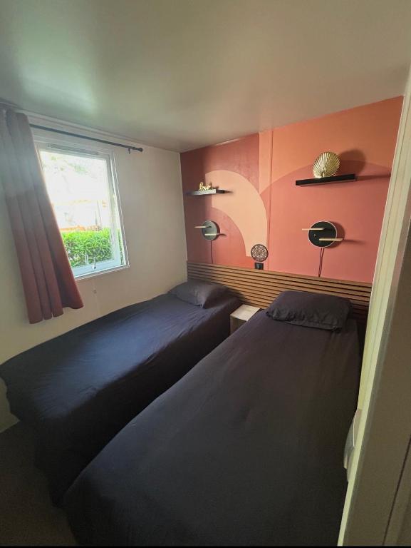 two beds in a small room with a window at Le SaraLéna in Torreilles