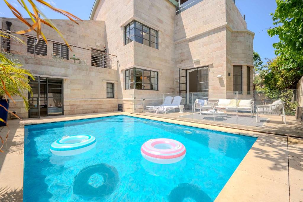 a house with a swimming pool with two frisbees in it at Carmelo I MOD Villa in Herzliya B