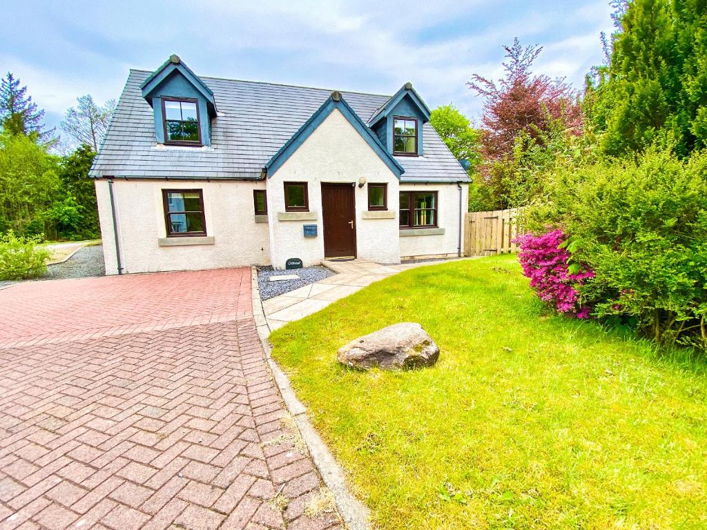 a house with a brick driveway in front of a yard at Lochindaal in Tarbert