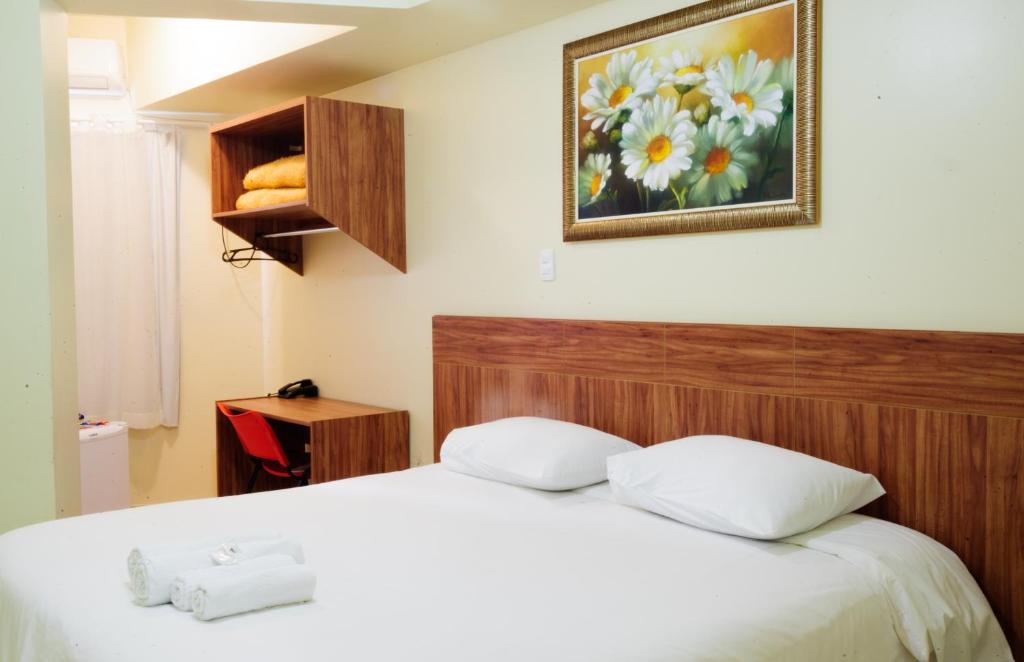 a bedroom with a bed and a picture of flowers at Caravelle Hotel in Guanhães