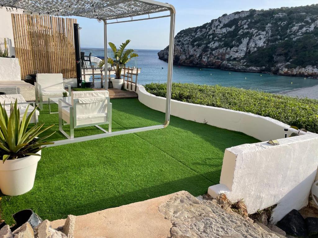 a lawn with chairs and a view of the ocean at Menorca Dreams, Acceso Directo a Playa in Cala en Porter