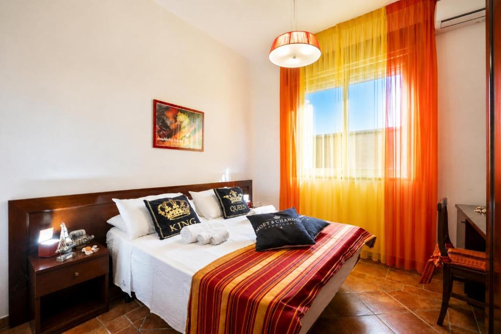 a bedroom with a bed and a window with orange curtains at Le Chele - A Due Passi dal Mare in Torre Lapillo