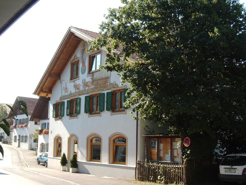 a white building with green shuttered windows on a street at Appartementhaus Marion in Bad Bayersoien