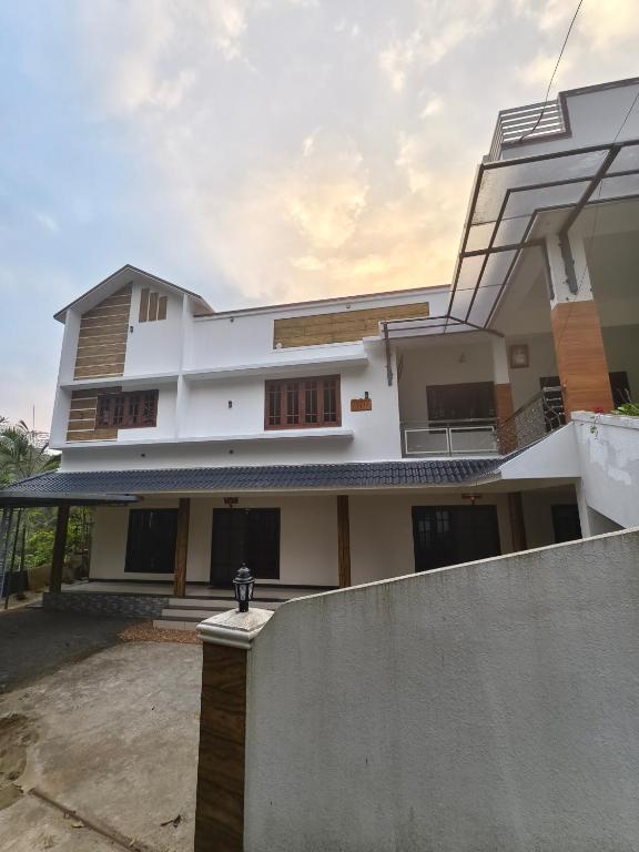 a white house with a fence in front of it at Periyarhills 2 BHK Budget villa Thekkady in Thekkady