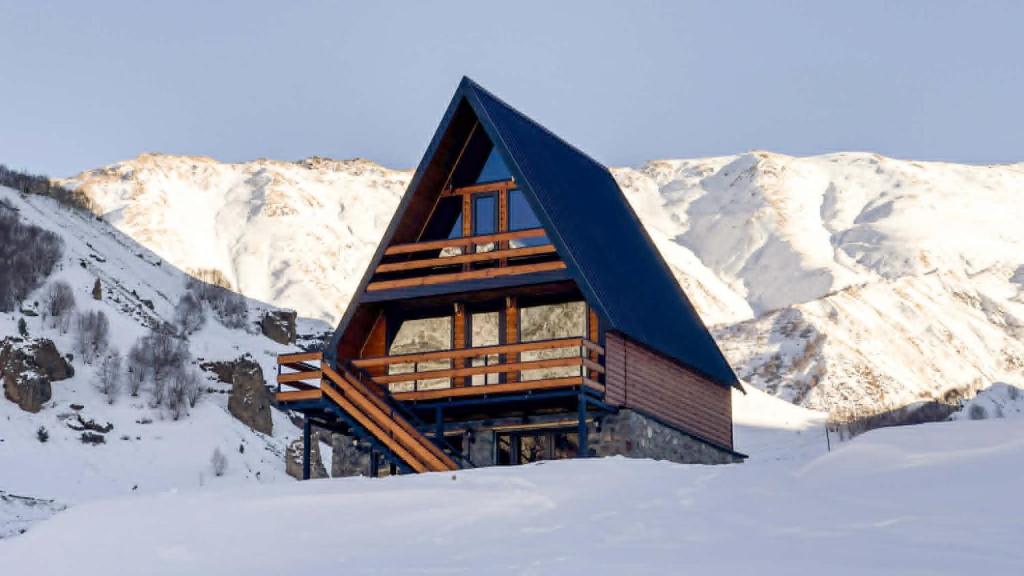 a cabin in the snow with mountains in the background at Eastlight Cottage in Gorists'ikhe
