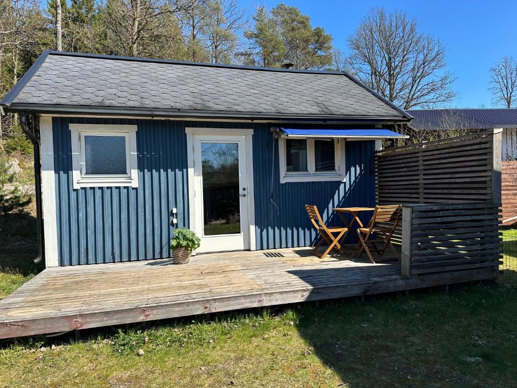 a blue shack with a table and chairs on a deck at Boende nära sjö i Gyltige Simlångsdalen in Simlångsdalen