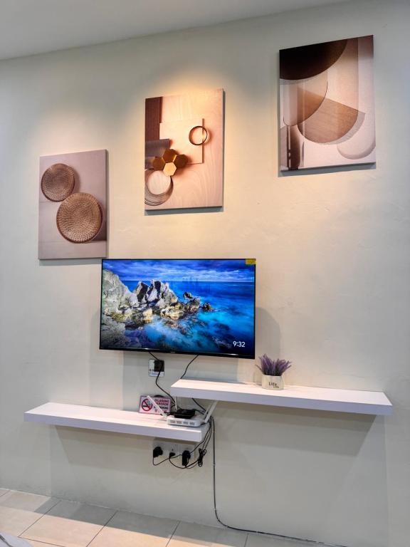 a desk with a computer on a wall with pictures at Howie Home in Ipoh