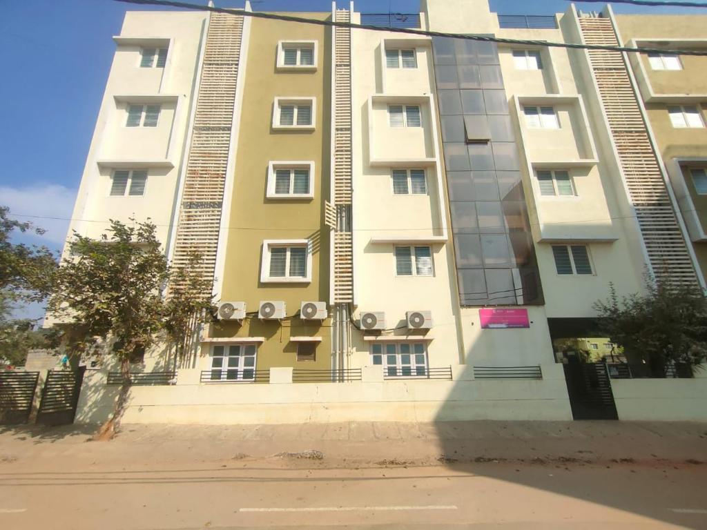 a tall white building with windows on a street at MVTJ Hotel in Bangalore