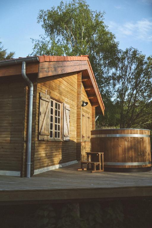 a small wooden cabin with a door and a bench at Le Chalet du Michel in Hardifort