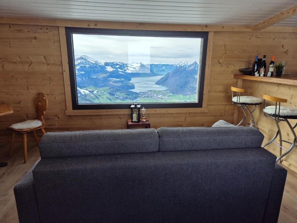 a couch in a room with a large window at Seilbahnstubli in Ibergeregg