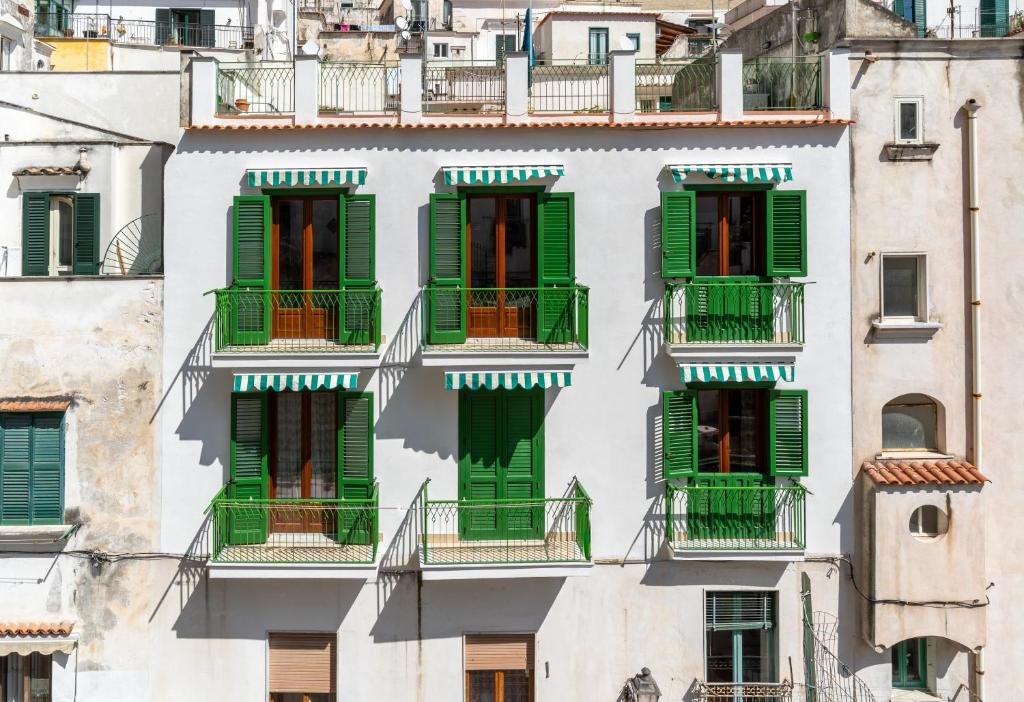 a facade of an apartment building with green shutters at CristallPont AmalfiDay in Atrani